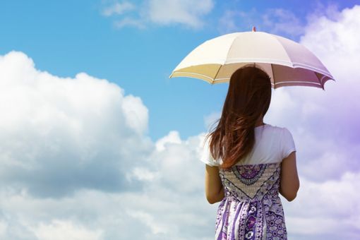 Frau mit Schirm vor Wolken