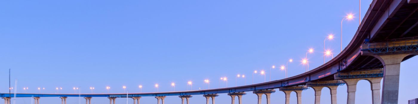 A close-up dusk view of Coronado Bridge, winding over calm San Diego Bay