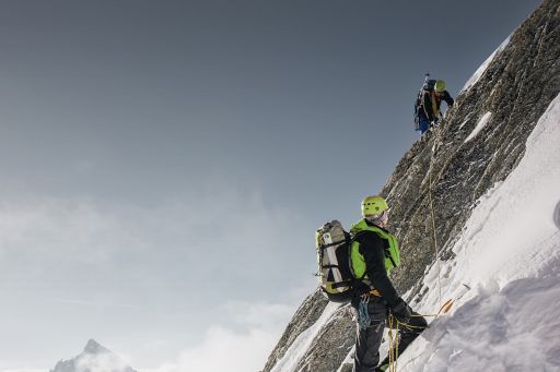 An expert mountain climber helping another climber