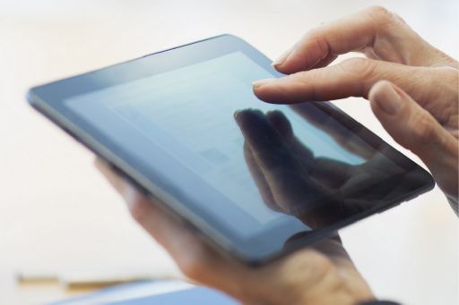 KPMG IFRS toolkit topic image: person using a digital tablet and a stack of reference manuals