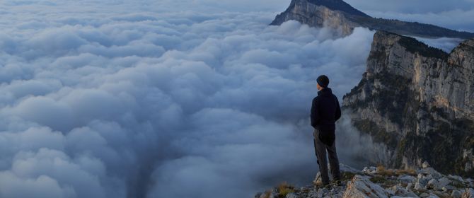 man looking over the cloud on top of a mountain