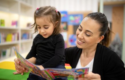uma mulher lendo um livro para uma criança em uma biblioteca
