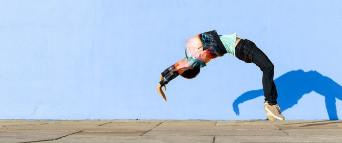 Person doing backflip in front of blue wall