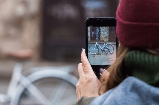 woman taking a picture of bicycle with mobile phone