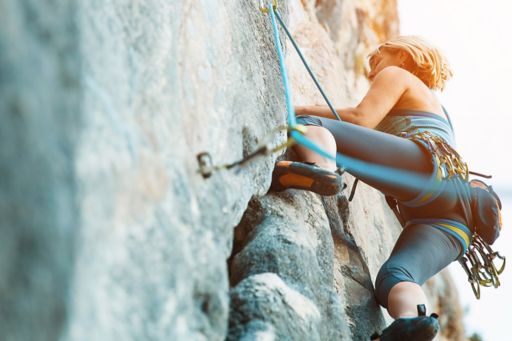 A woman rock climbing on a vertical flat wall
