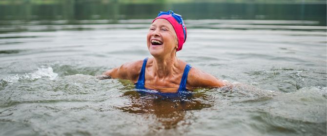 An active senior woman swims in a lake