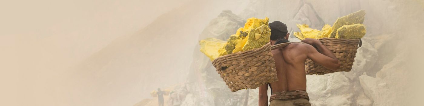 Asian worker carrying baskets of sulfur in Ijen volcano