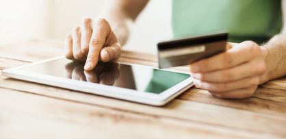 Man using tablet with credit card in other hand