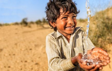 Boy child smiling as water is poured into his hands