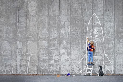 Boy drawing rocket on wall with chalk
