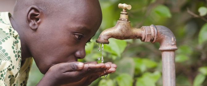 Boy drinking water through tap