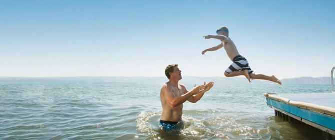 Boy jumping into a lake into his father's arms