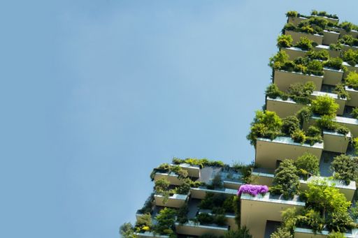 Apartment building with green plants on balconies against a blue sky