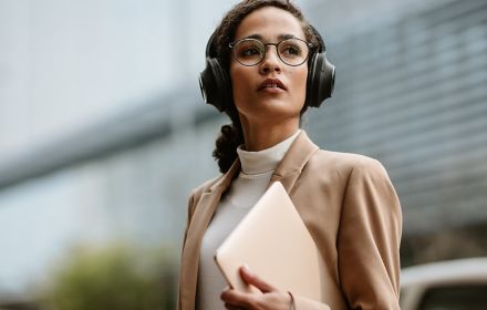 Businesswoman with headphones walking down the street