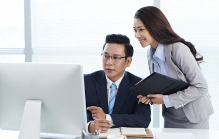 businessman and his assistant looking at computer screen