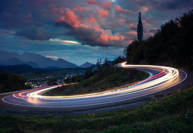 Cars light trails on road with circular turn