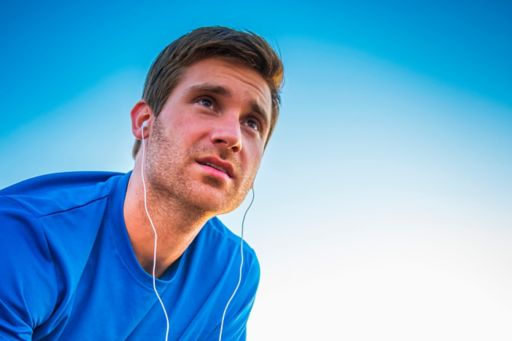 Caucasian runner resting and listening to mp3 player