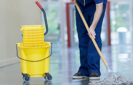 Hospital worker in blue scrubs mopping floor