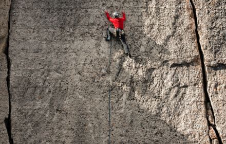 Cliff mountain climber wearing a red outfit