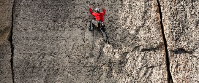 Cliff mountain climber wearing red outfit