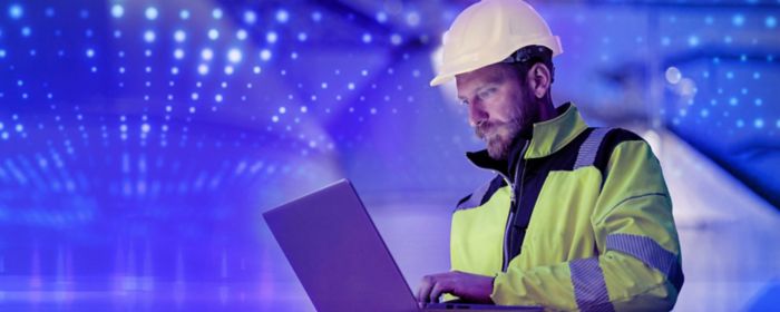 Construction industry technician in hardhat using laptop