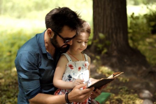 dad-with-daughter-reading-book-in-park