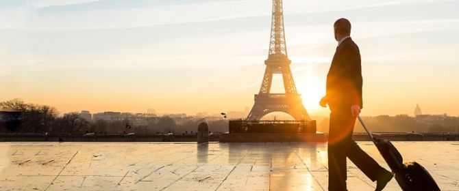 Mann mit Koffer vor dem Eiffelturm