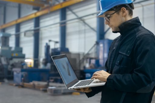 Factory worker in hard hat using a laptop