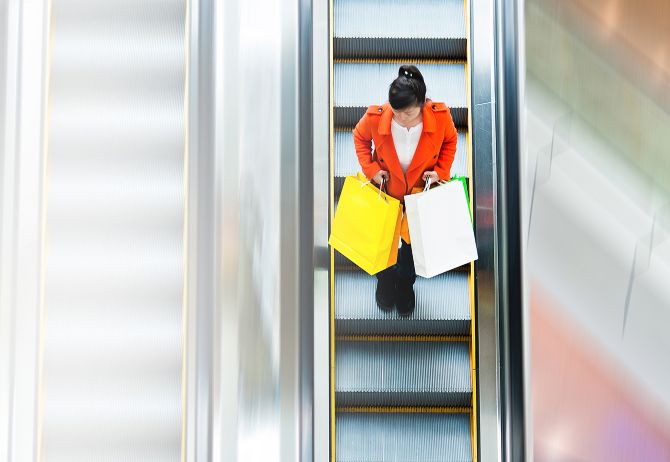 Frau mit Tüten auf Rolltreppe