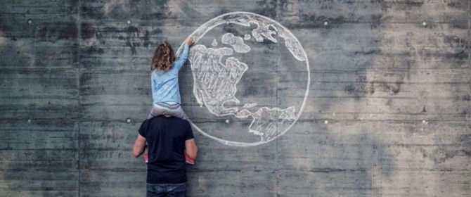 Girl drawing earth on wall sitting on fathers shoulders