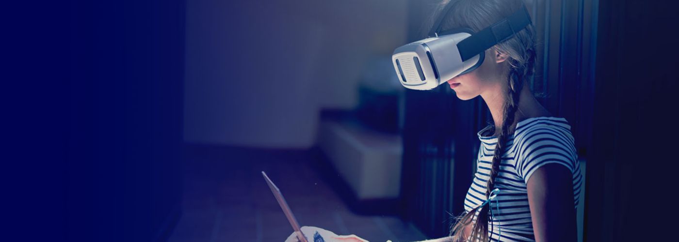 Girl wearing virtual reality goggles using laptop