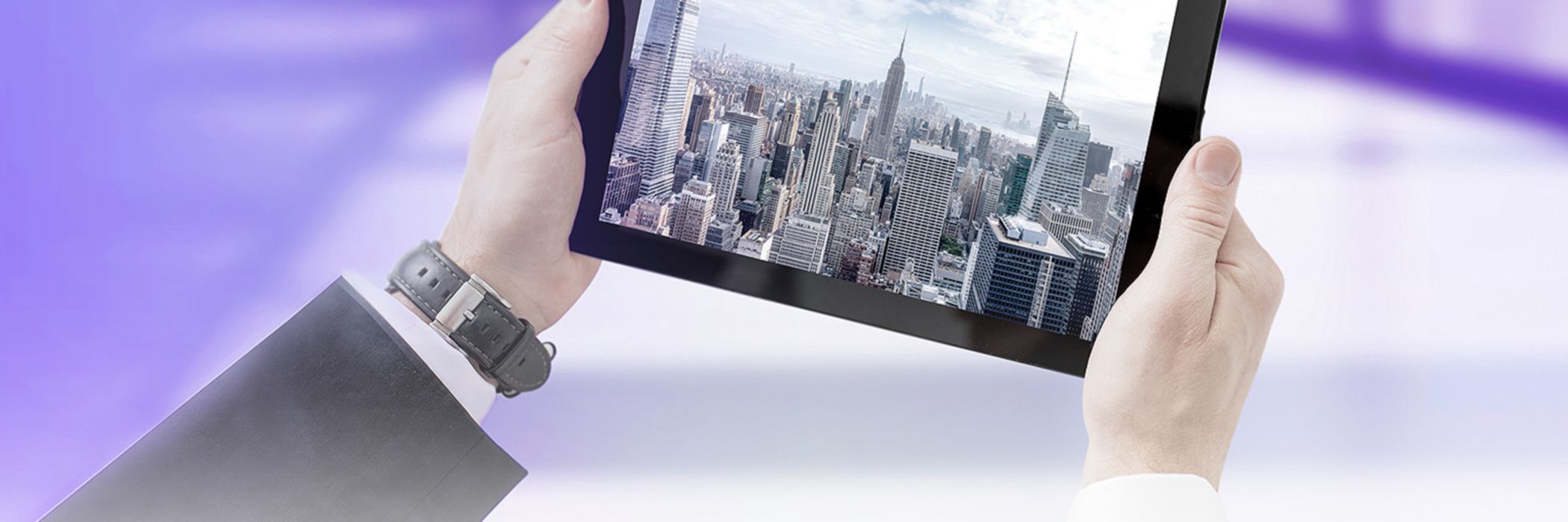Hands holding tablet showing a skyline