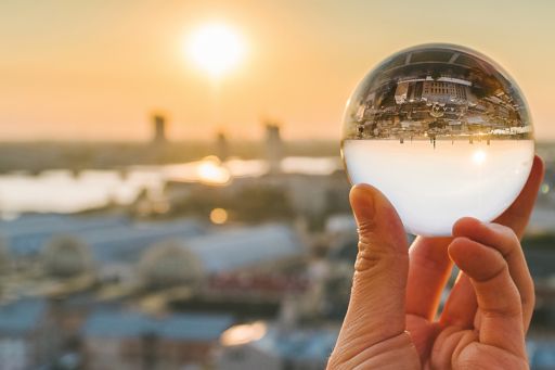 Cropped Image Of Hand Holding Crystal Ball Against City