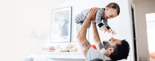 Happy father lifting daughter while sitting on sofa at home