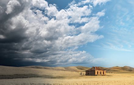 House in a dry field with storm clouds approaching