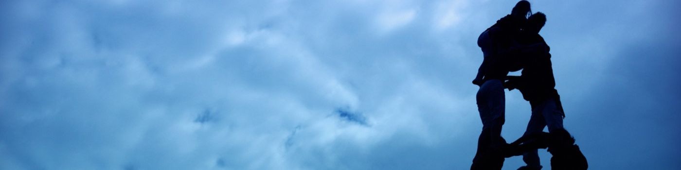 Human pyramid against a blue, cloudy sky