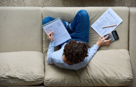 Man sitting on couch making calculations