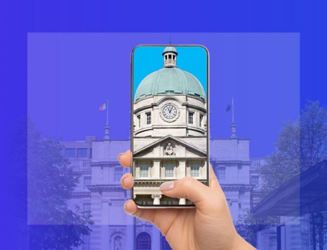 Hand holding phone up to Government buildings with rotunda displayed clearly on phone