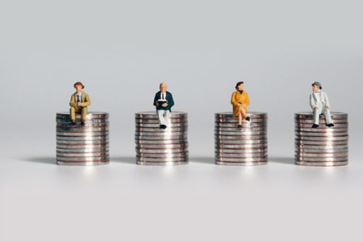 Miniature people sitting on stacks of coins