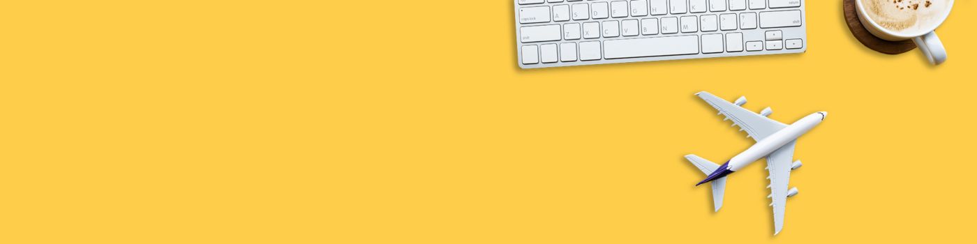 Miniature plane on yellow desktop with cactus, keyboard and coffee
