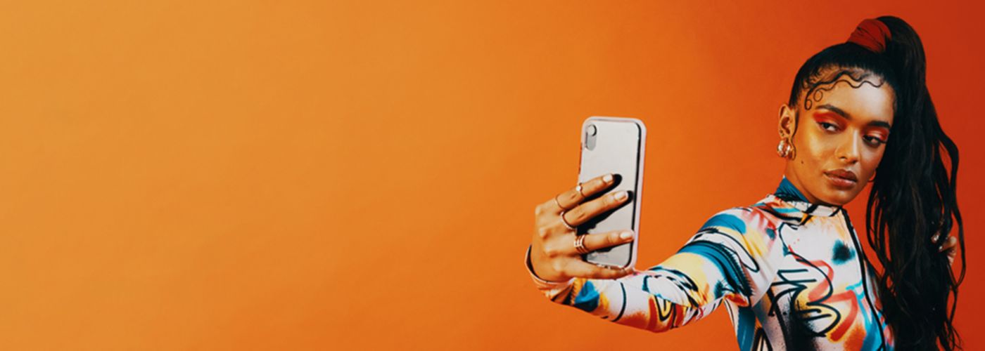 Frau macht Selfie vor orangem Hintergrund
