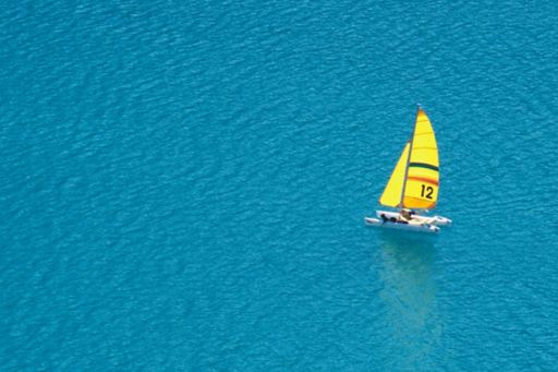 Financial instruments | Trimaran with a yellow sail on the open water