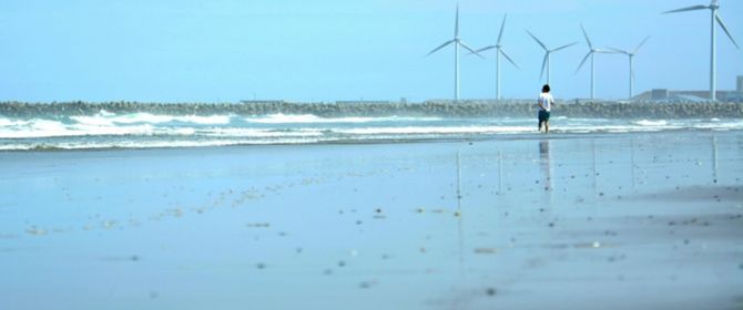 風車がある海岸に佇む男性