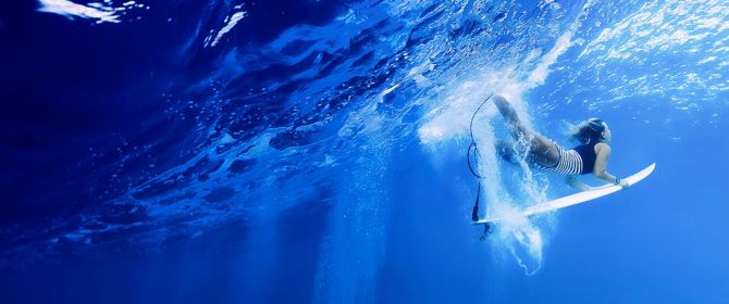 femal surver diving under wave