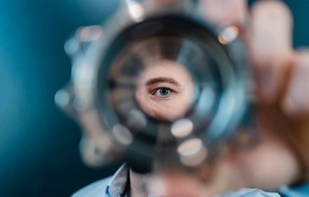 Male professional's eye looking through a circular machine part