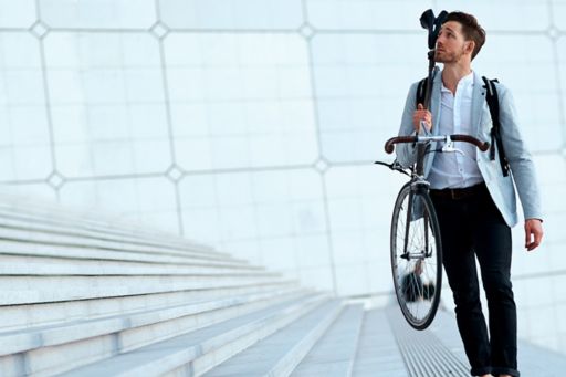 Man wearing blazer shows holding bicycle beside stairs
