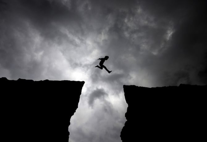 Man jumping from cliff - Dark clouds