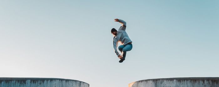 Man jumping high mid air on concrete bridge