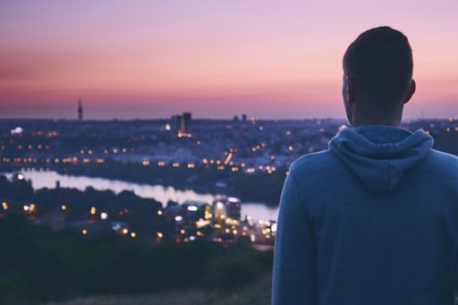 Man looking at city over a river at sunset