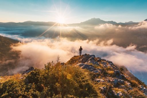 Man standing on mountain cliff above the clouds